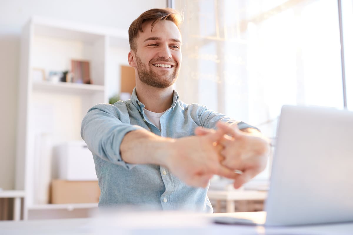 Mann stretcht sich am Schreibtisch