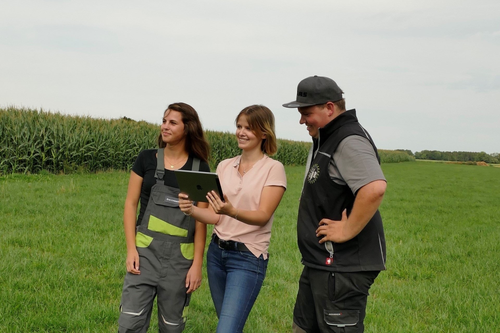 Two young girls with a tablet in a field. Young women on a field with a tablet.